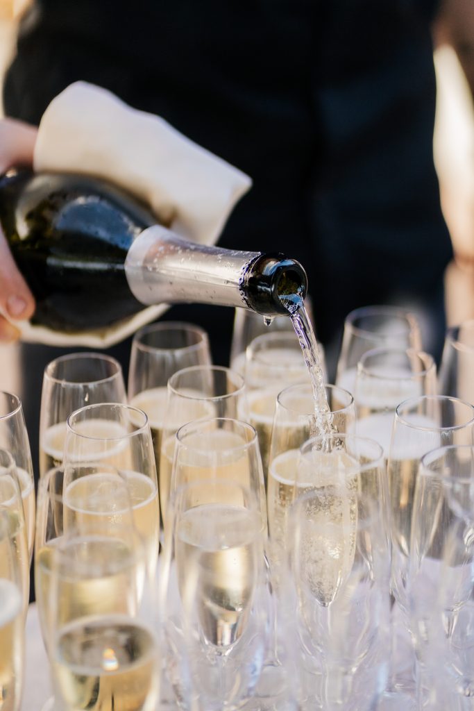 Ein Flasche Sekt und viele bereits gefüllte Sektgläser in Nahaufnahme