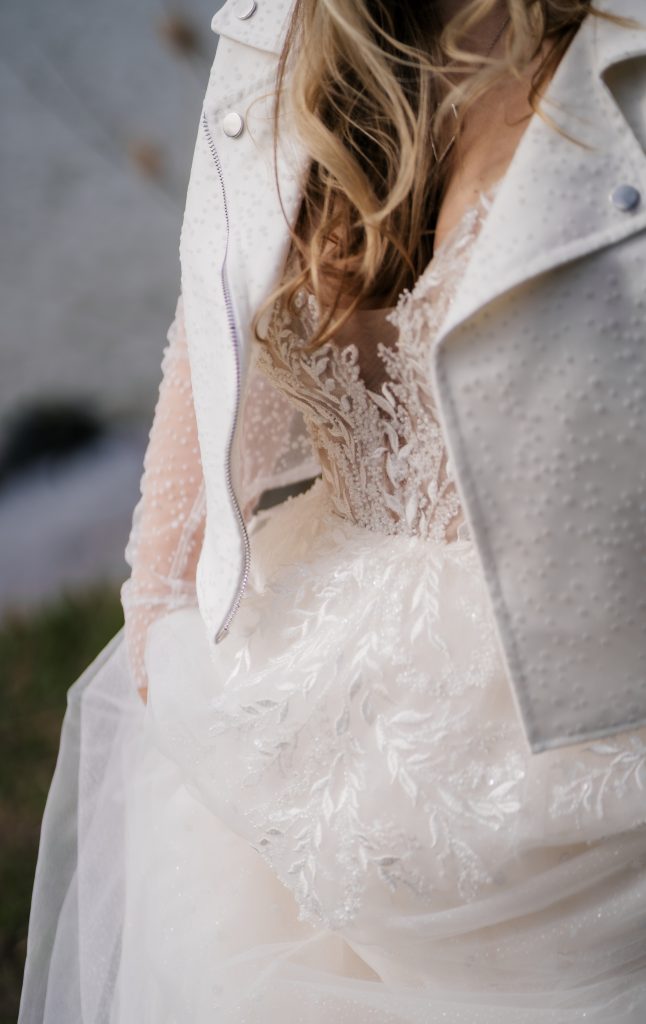 Eine Braut mit spitzenbesetzten Brautkleid und einer weißen Jacke.